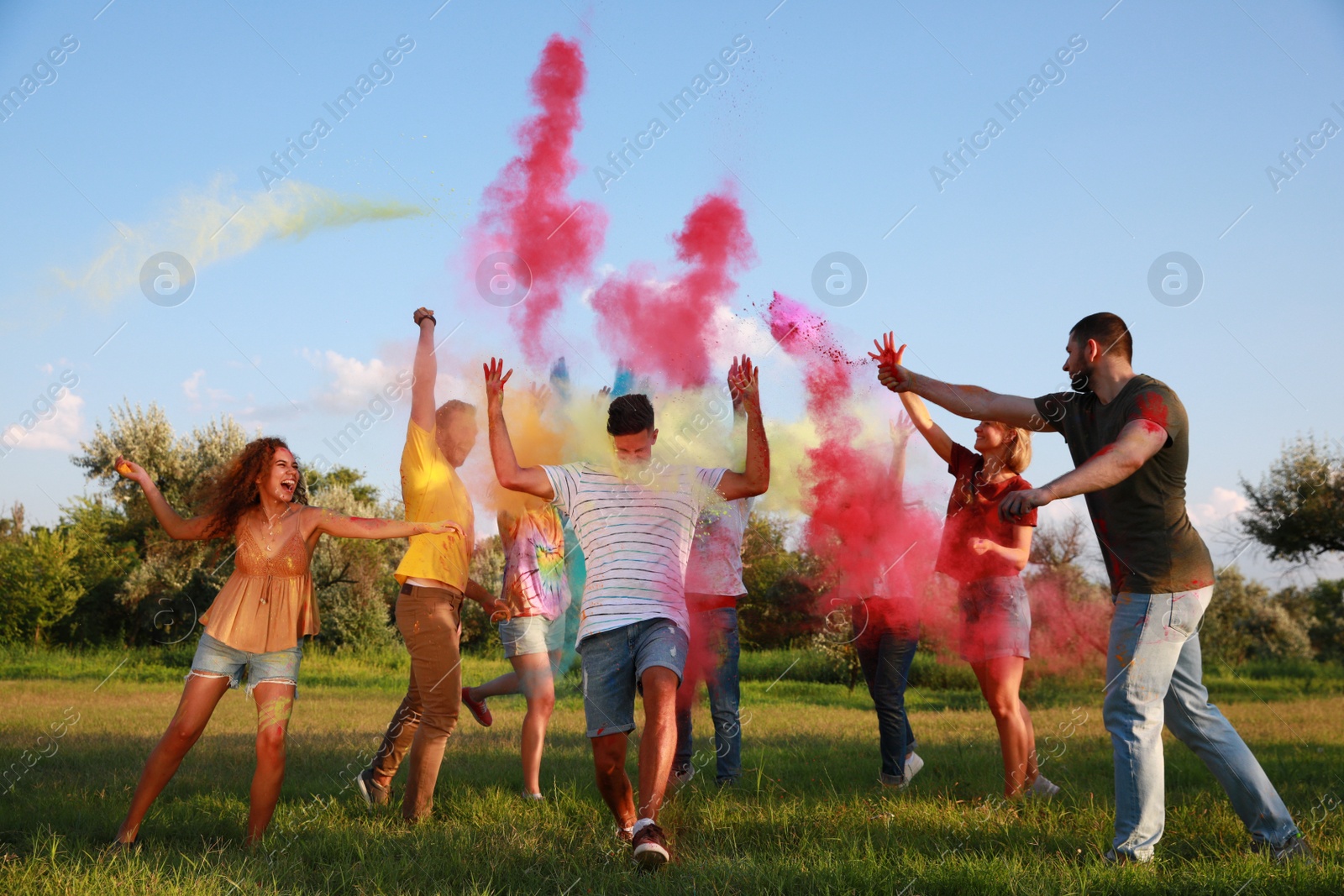 Photo of Happy friends having fun with colorful powder dyes outdoors. Holi festival celebration