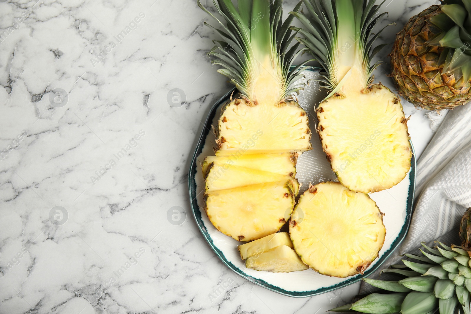 Photo of Tasty cut pineapples on white marble table, flat lay. Space for text