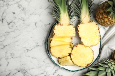 Photo of Tasty cut pineapples on white marble table, flat lay. Space for text