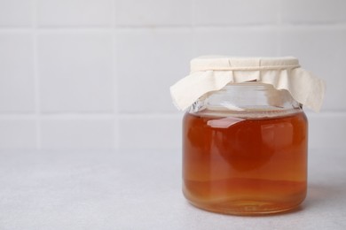 Photo of Tasty kombucha in glass jar on white table, space for text