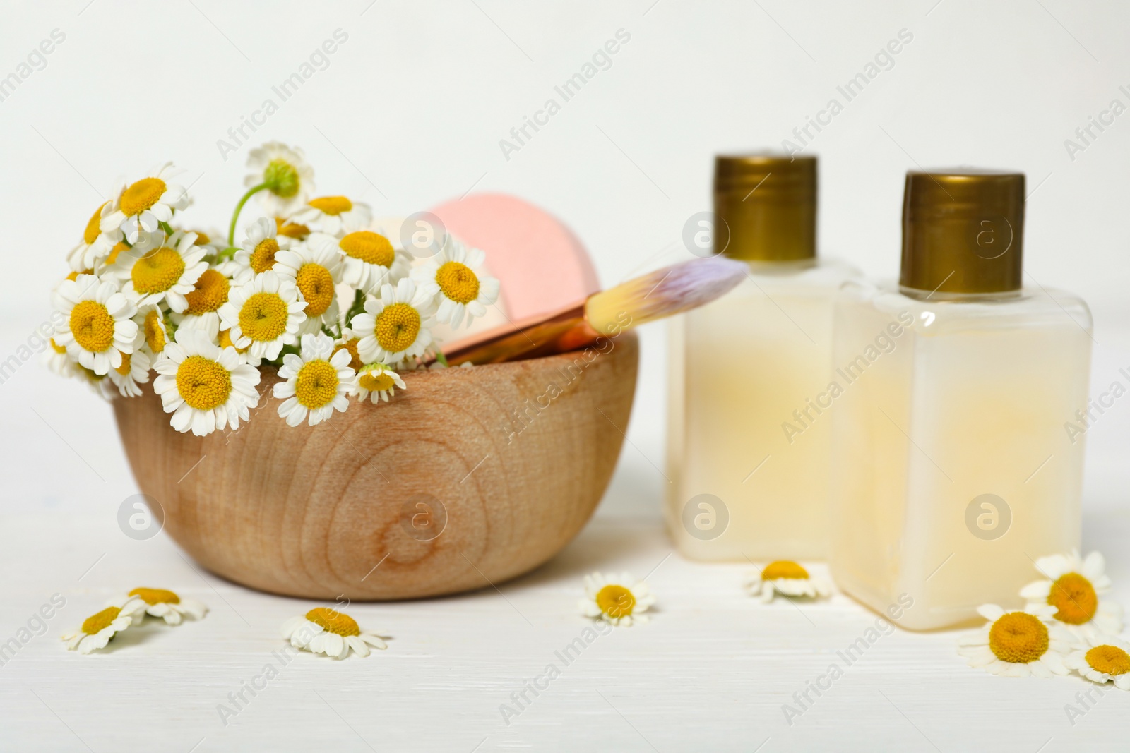 Photo of Cosmetic products, beauty accessories and chamomiles on white wooden table