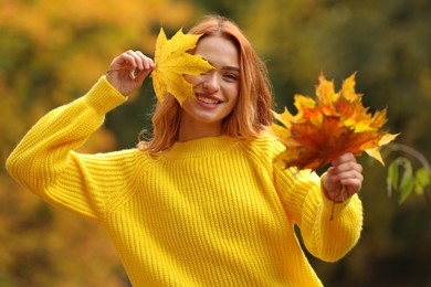 Portrait of happy woman with autumn leaves outdoors