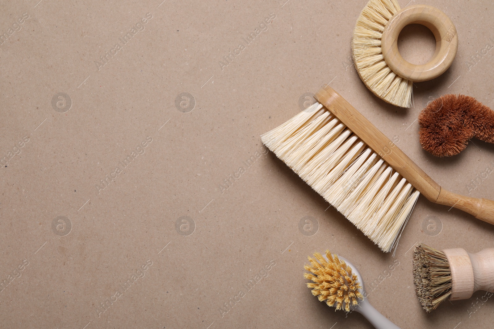 Photo of Cleaning brushes on pale brown background, flat lay. Space for text