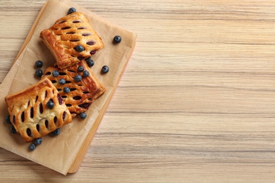 Photo of Fresh delicious puff pastry with fresh berries served on wooden table, top view. Space for text