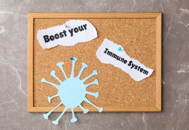 Photo of Paper pieces with phrase Boost your Immune System pinned to corkboard on grey background