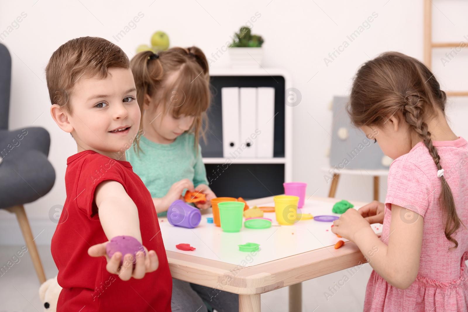 Photo of Cute little children using play dough at table indoors