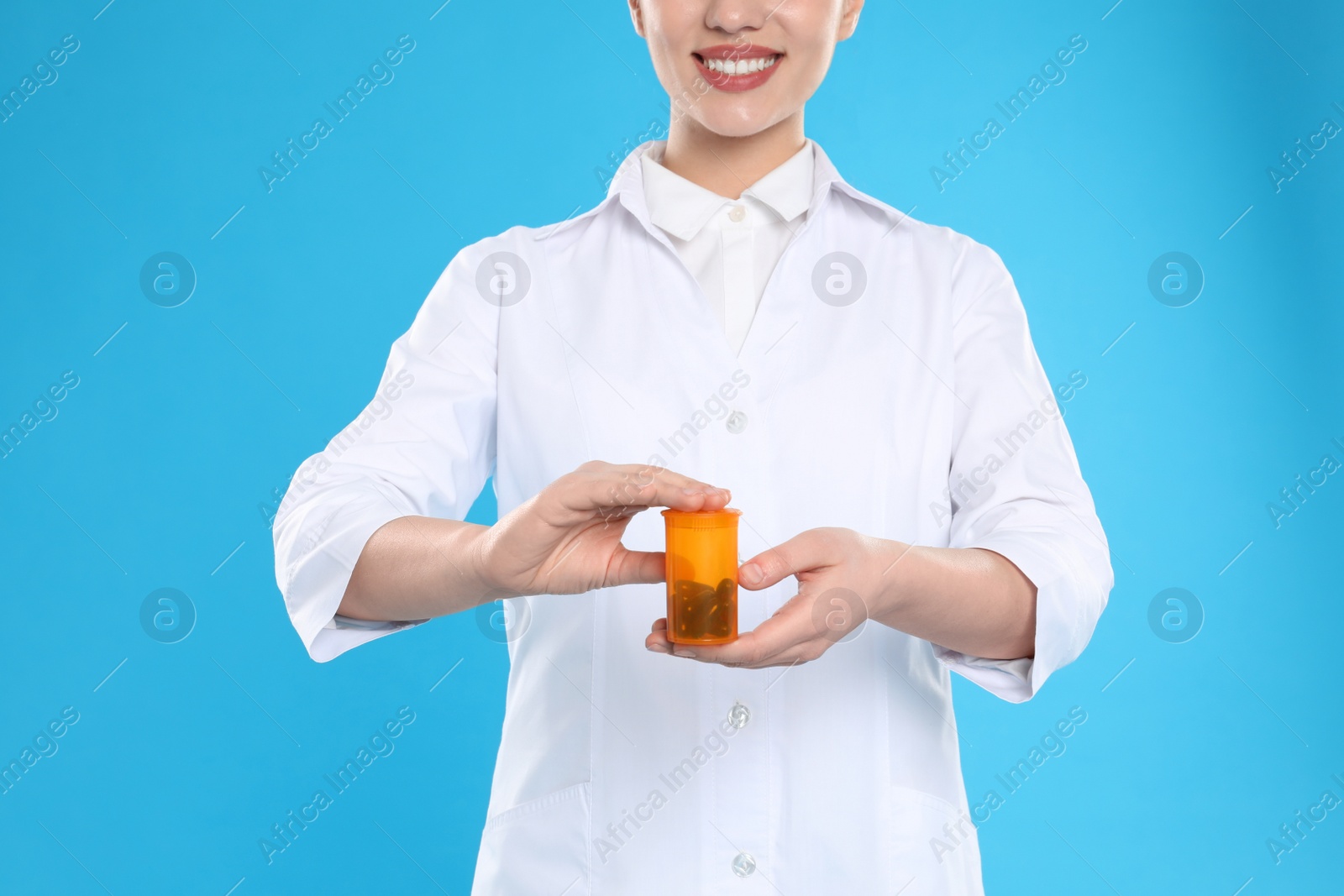 Photo of Professional pharmacist with pills on light blue background, closeup