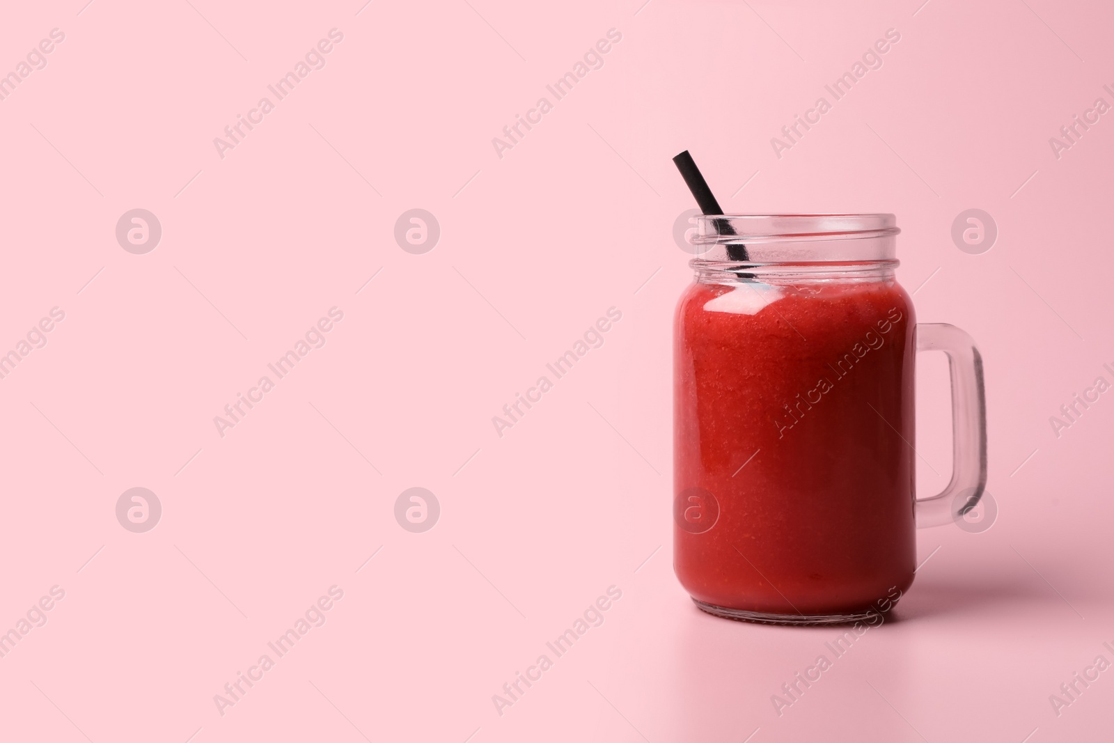 Photo of Mason jar with delicious berry smoothie on pink background. Space for text