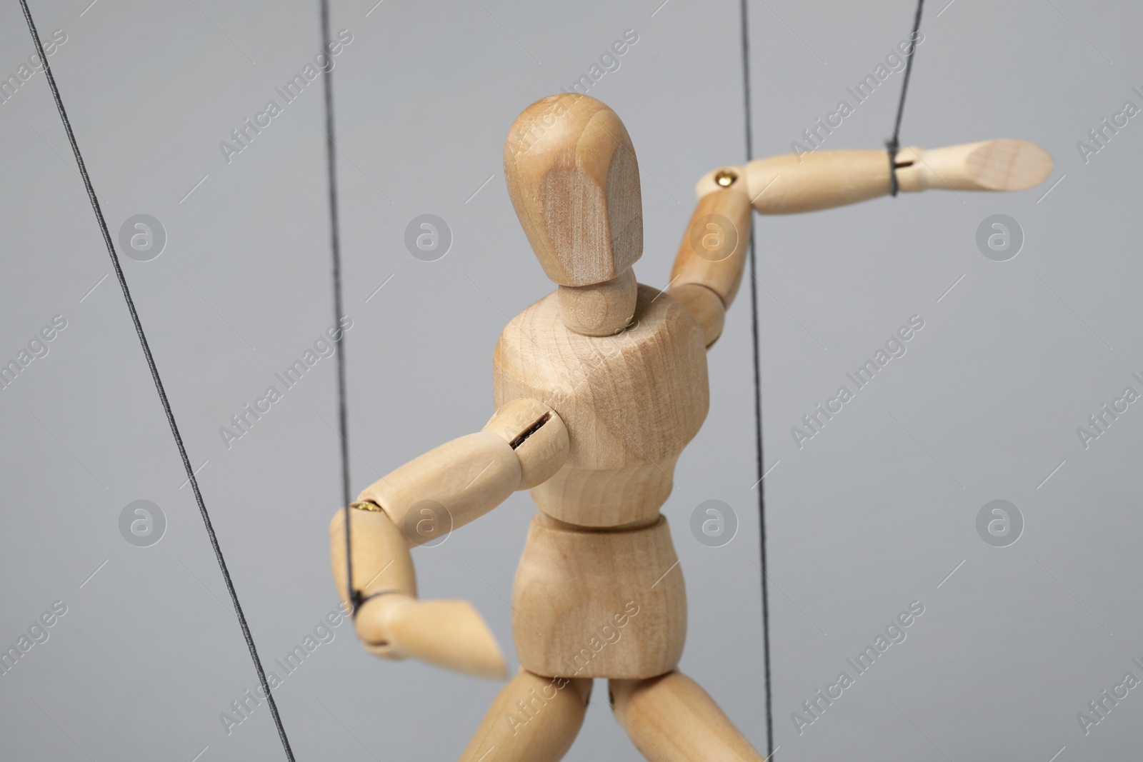 Photo of One wooden puppet with strings on light grey background