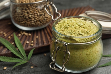 Photo of Jar of hemp protein powder on grey stone table, closeup