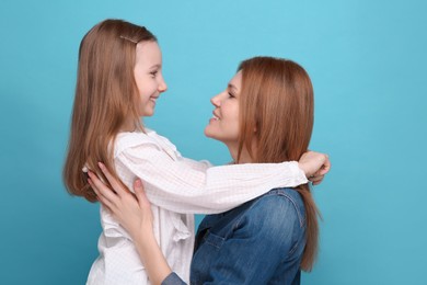 Photo of Portrait of happy mother and her cute daughter on light blue background