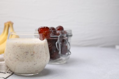 Glass of delicious date smoothie on white table
