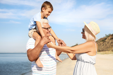 Photo of Cute little boy with grandparents spending time together on sea beach