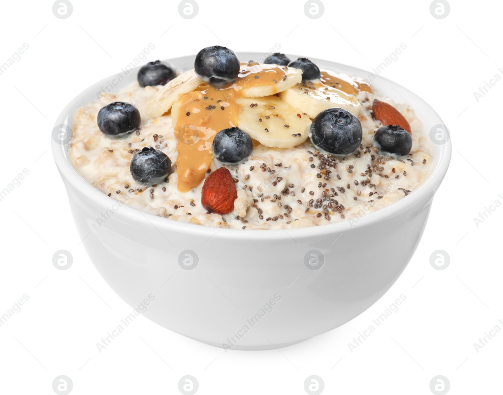 Photo of Tasty boiled oatmeal with blueberries, banana, chia seeds almonds and peanut butter in bowl isolated on white