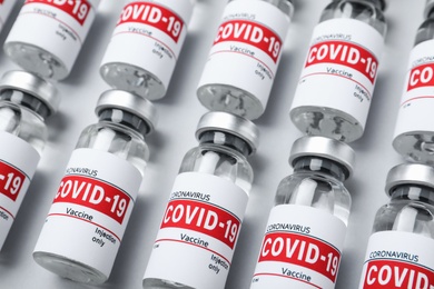 Glass vials with COVID-19 vaccine on light grey background