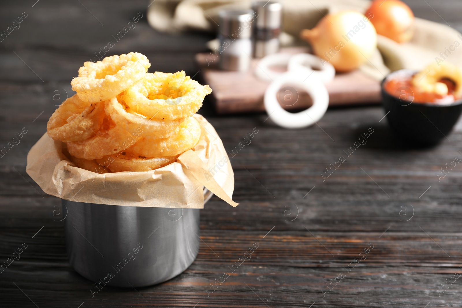 Photo of Dishware with homemade crunchy fried onion rings on wooden table. Space for text