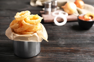 Photo of Dishware with homemade crunchy fried onion rings on wooden table. Space for text