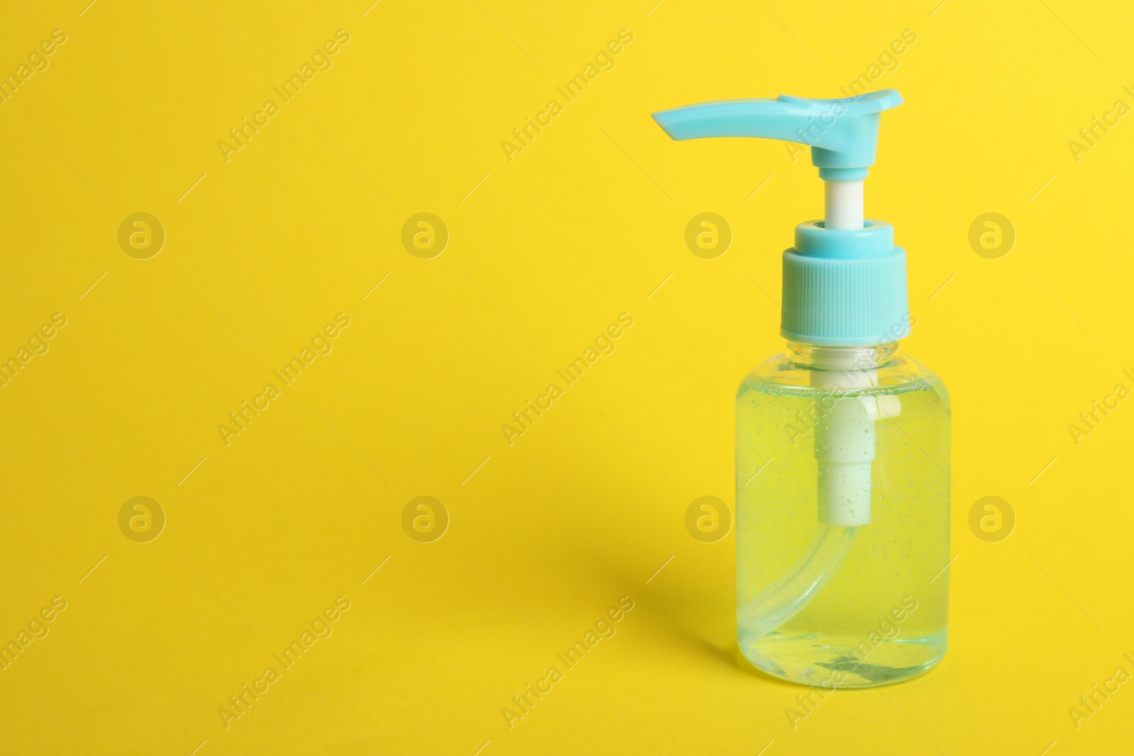 Photo of Dispenser bottle with antiseptic gel on yellow background. Space for text