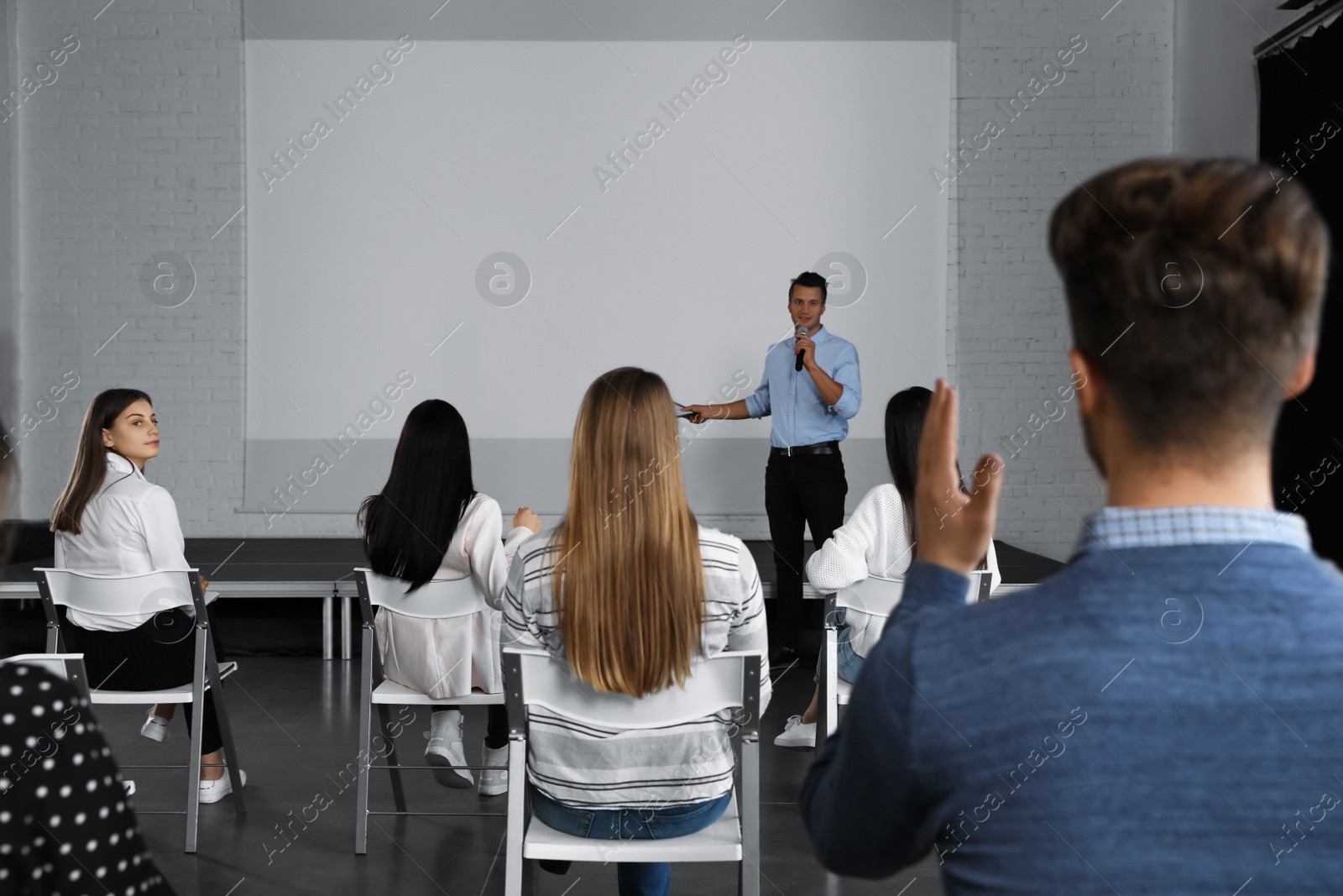 Photo of Male business trainer giving lecture in conference room with projection screen