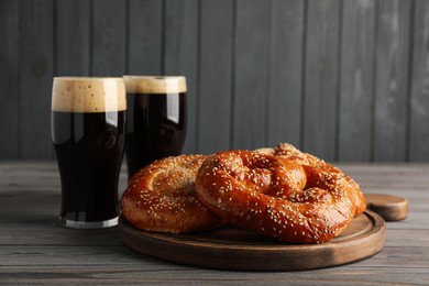 Photo of Tasty pretzels and glasses of beer on wooden table, space for text