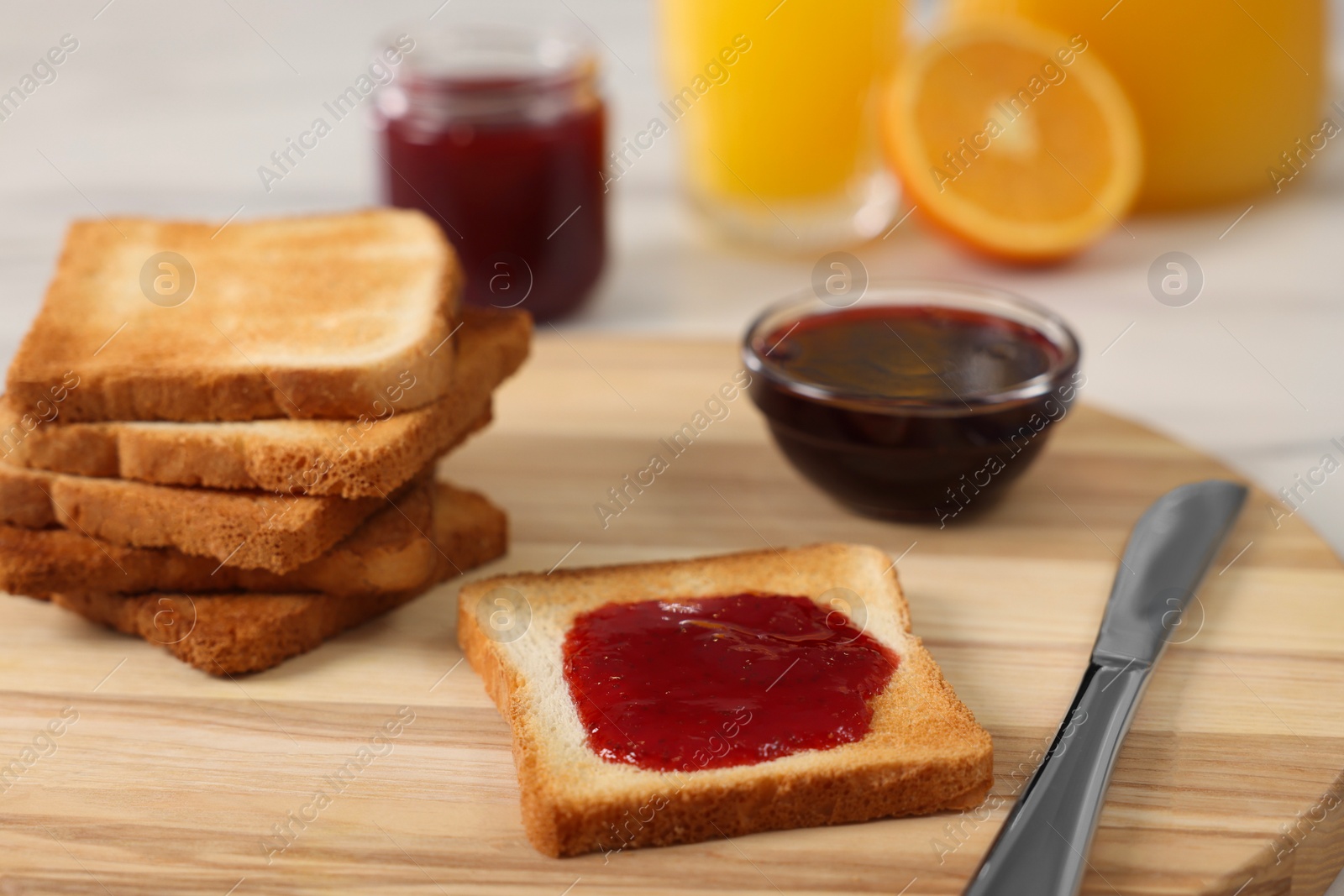 Photo of Breakfast time. Crunchy toasts and jam on wooden board, closeup