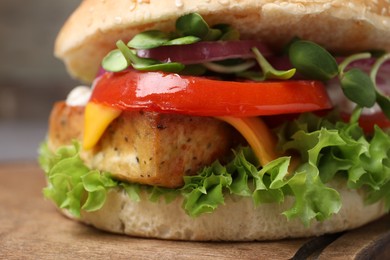 Delicious burger with tofu and fresh vegetables on wooden board, closeup