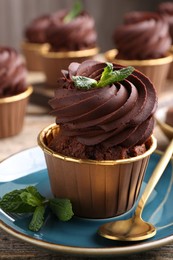 Photo of Delicious chocolate cupcake with mint on table, closeup