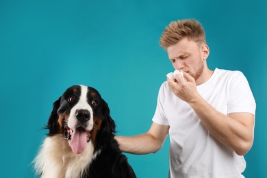 Photo of Young man suffering from fur allergy on blue background