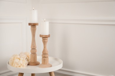 Photo of Elegant candlesticks with burning candles and flower on white table. Space for text