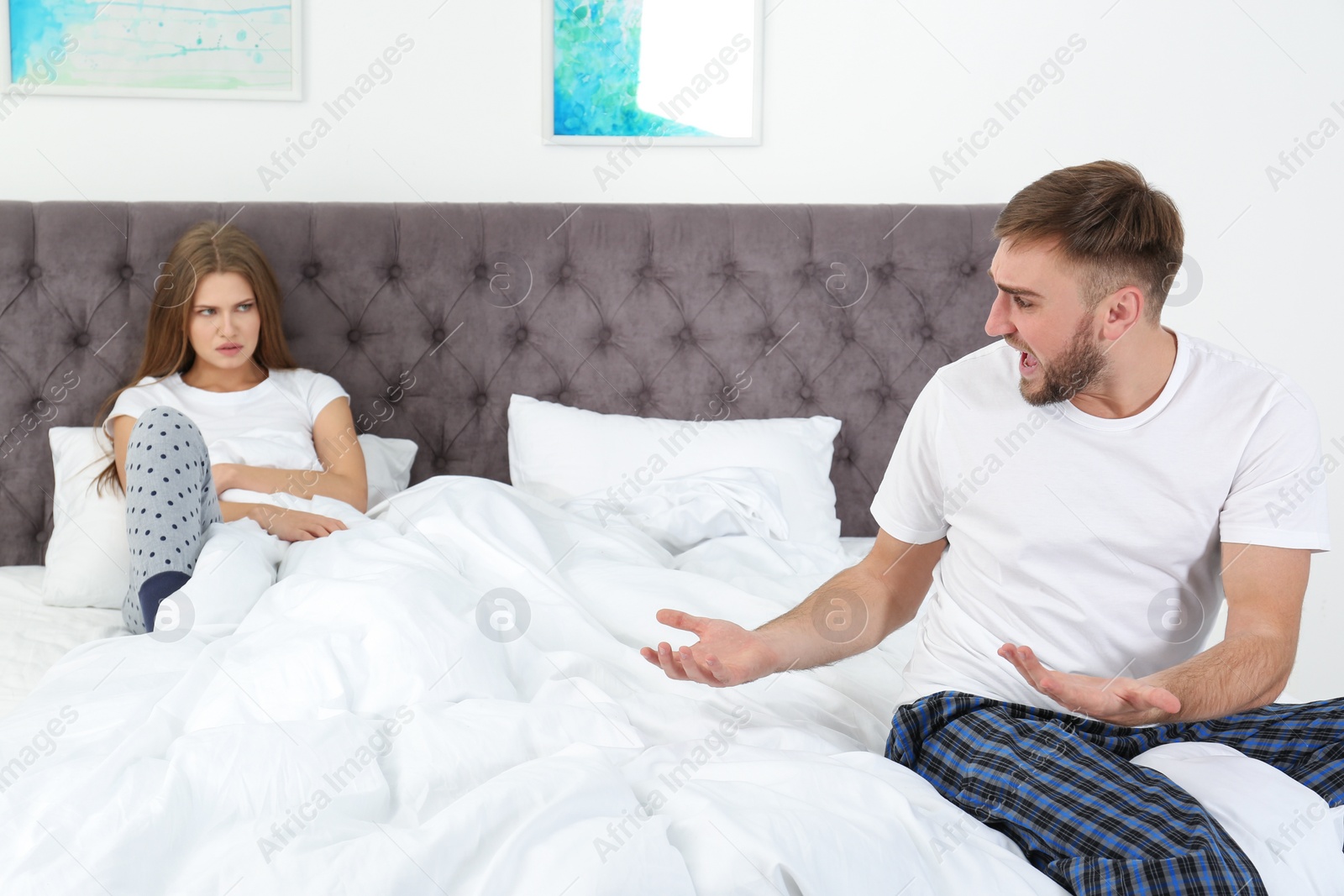 Photo of Young couple arguing in bedroom. Relationship problems