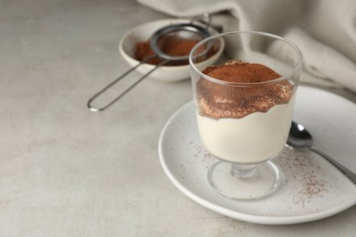 Photo of Delicious tiramisu in glass on light table. Space for text