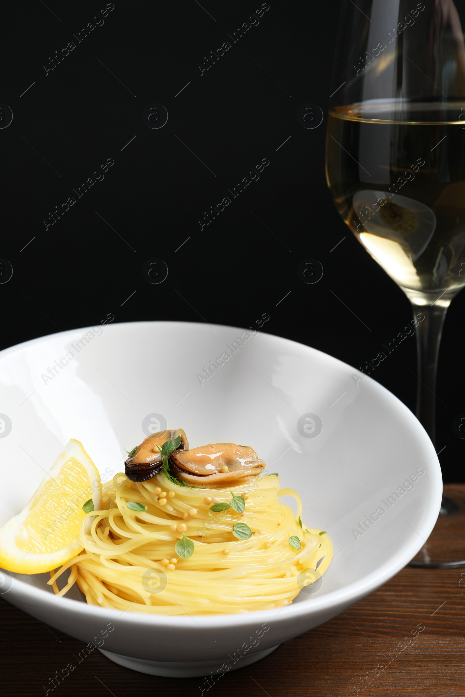 Photo of Tasty capellini with mussels and lemon on wooden table, closeup. Exquisite presentation of pasta dish