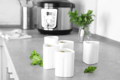 Photo of Containers with delicious fresh yogurt made in modern multi cooker on table