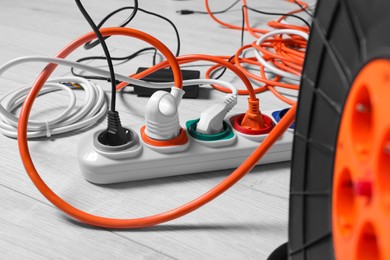 Extension cord reel plugged into power strip indoors, closeup. Electrician's equipment