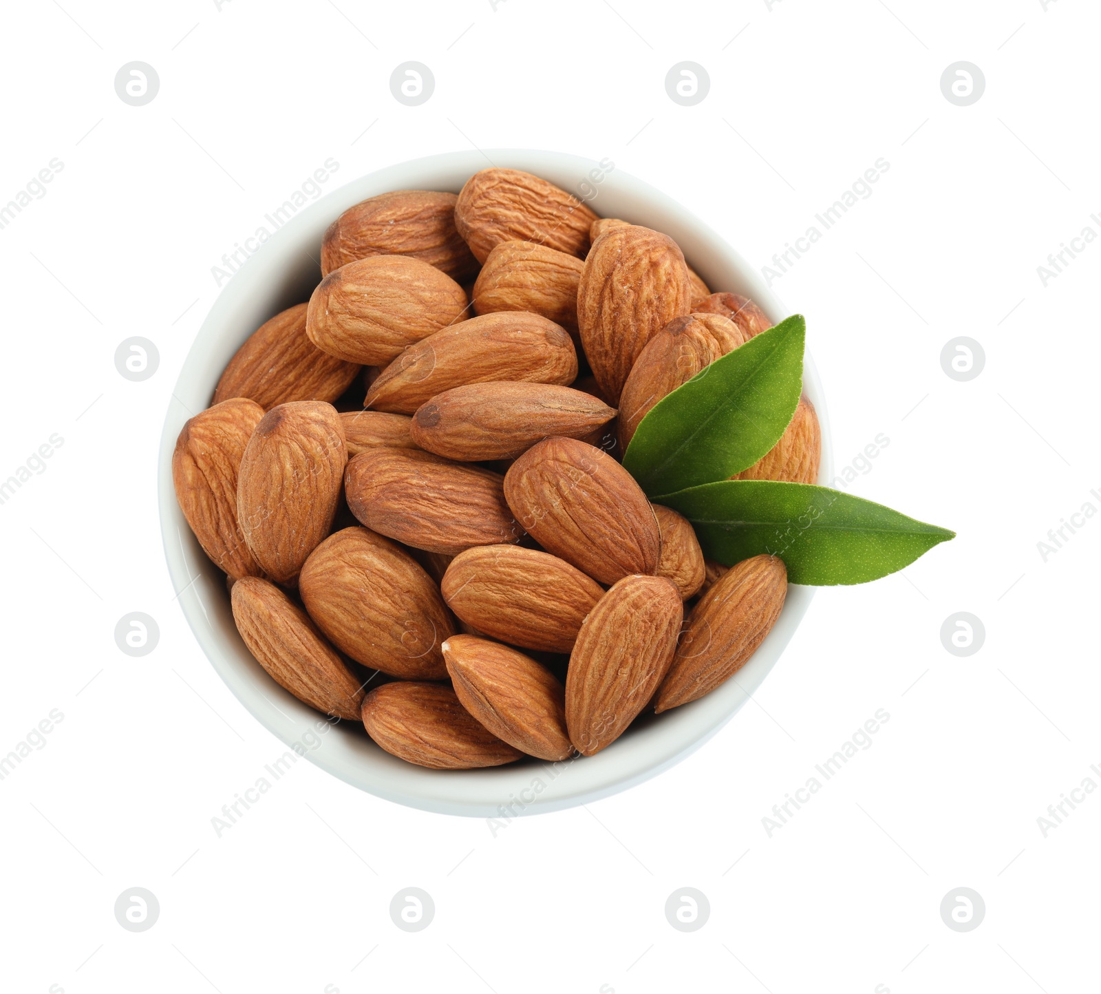 Photo of Bowl with organic almond nuts and green leaves on white background, top view. Healthy snack