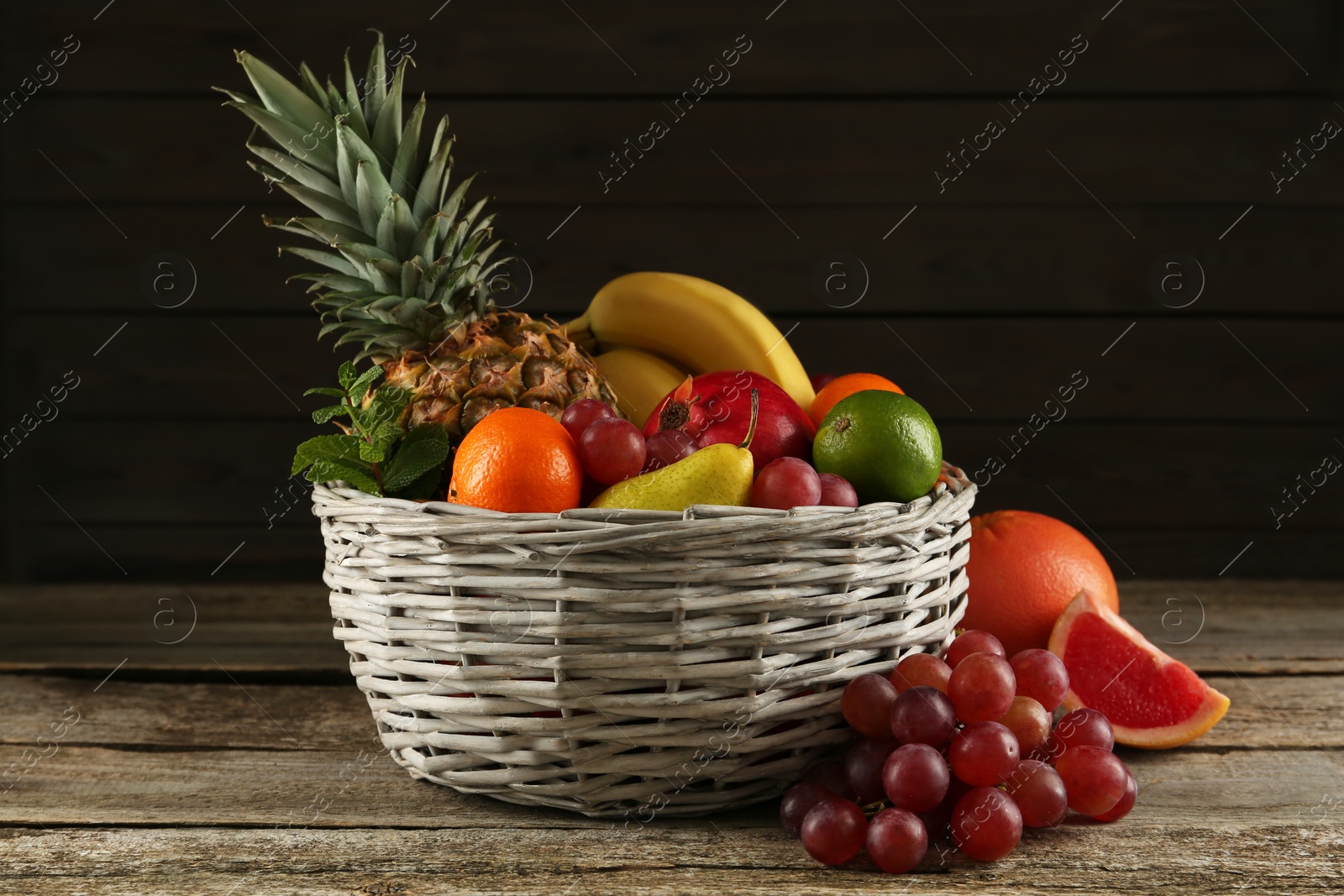 Photo of Fresh ripe fruits and wicker bowl on wooden table