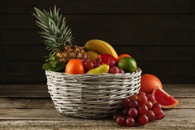 Photo of Fresh ripe fruits and wicker bowl on wooden table
