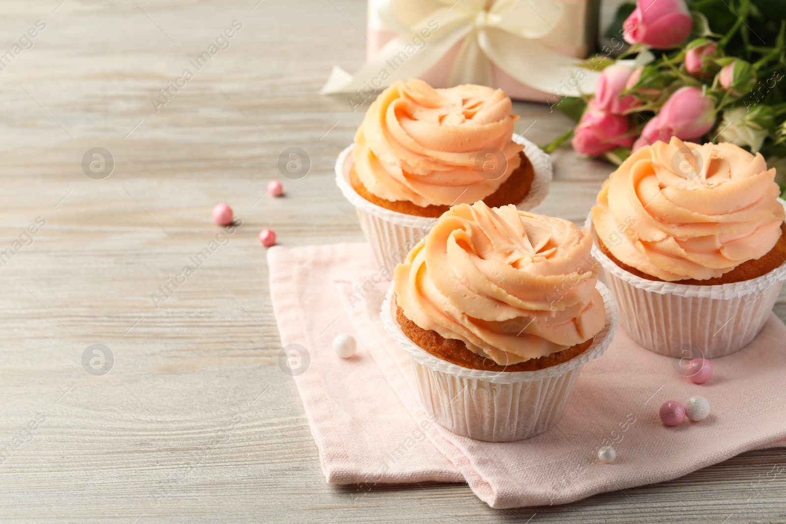 Photo of Tasty cupcakes with cream on wooden table, space for text