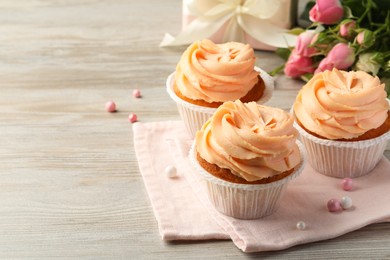 Tasty cupcakes with cream on wooden table, space for text