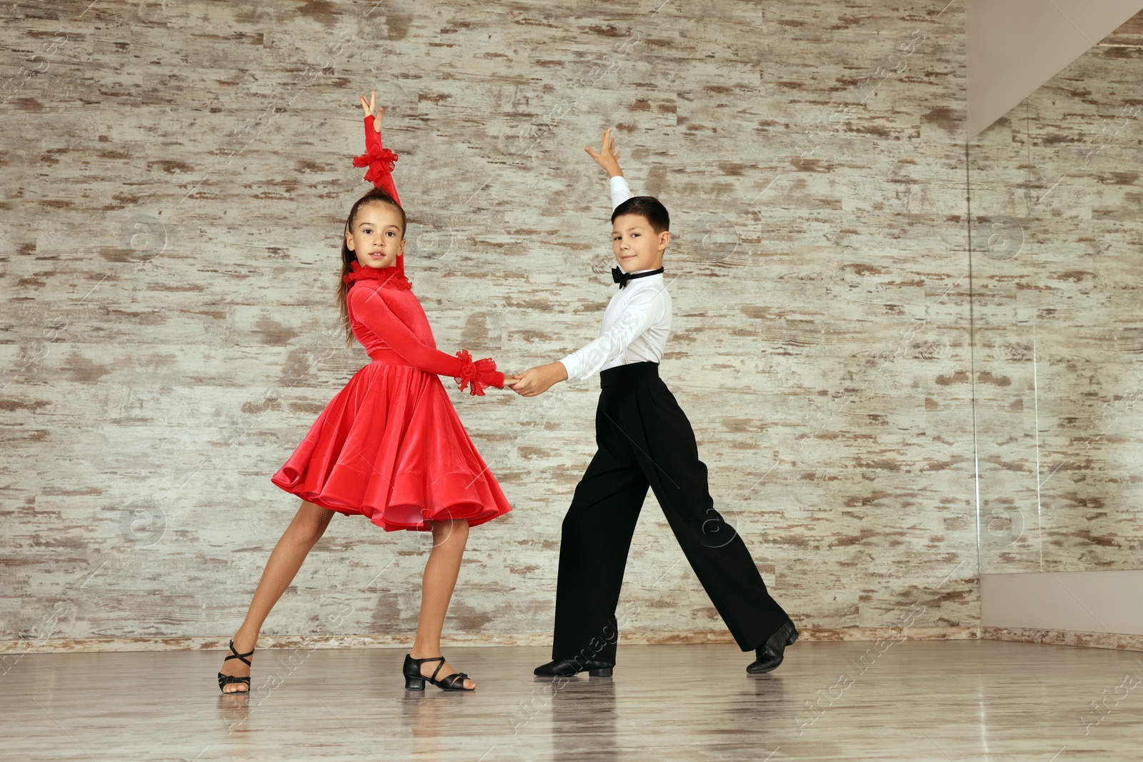 Photo of Beautifully dressed couple of kids dancing together in studio