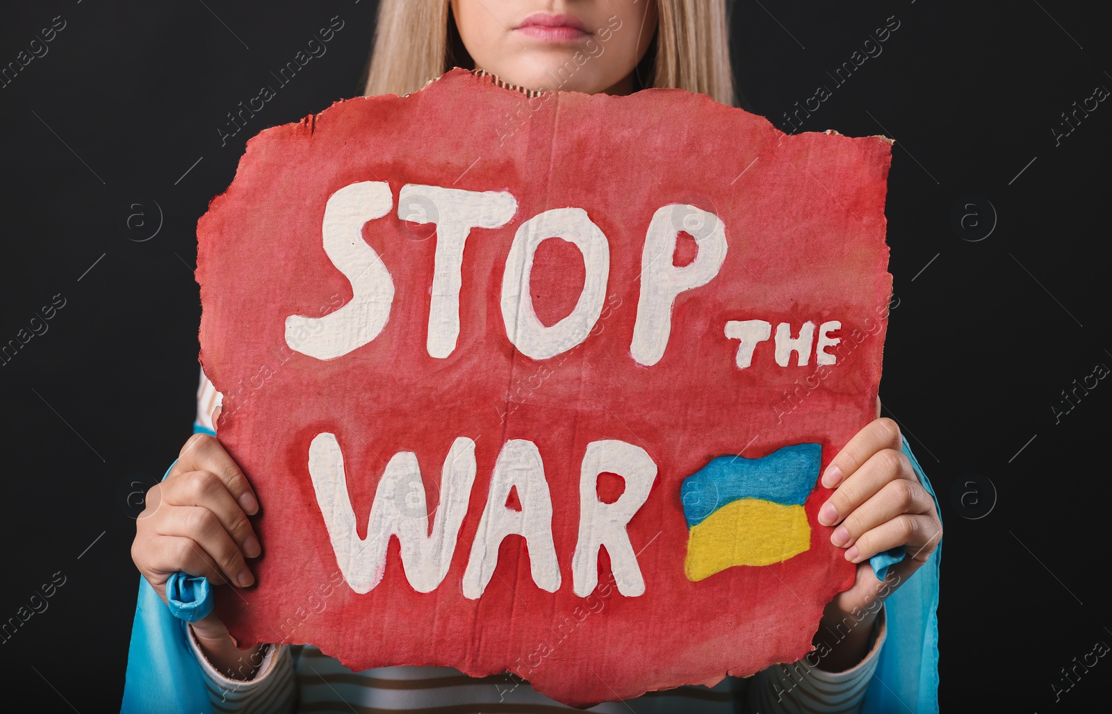 Photo of Sad woman holding poster with words Stop the War on black background, closeup