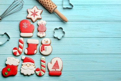 Photo of Kitchen utensils near Christmas tree shape made of delicious gingerbread cookies on light blue wooden table, flat lay. Space for text