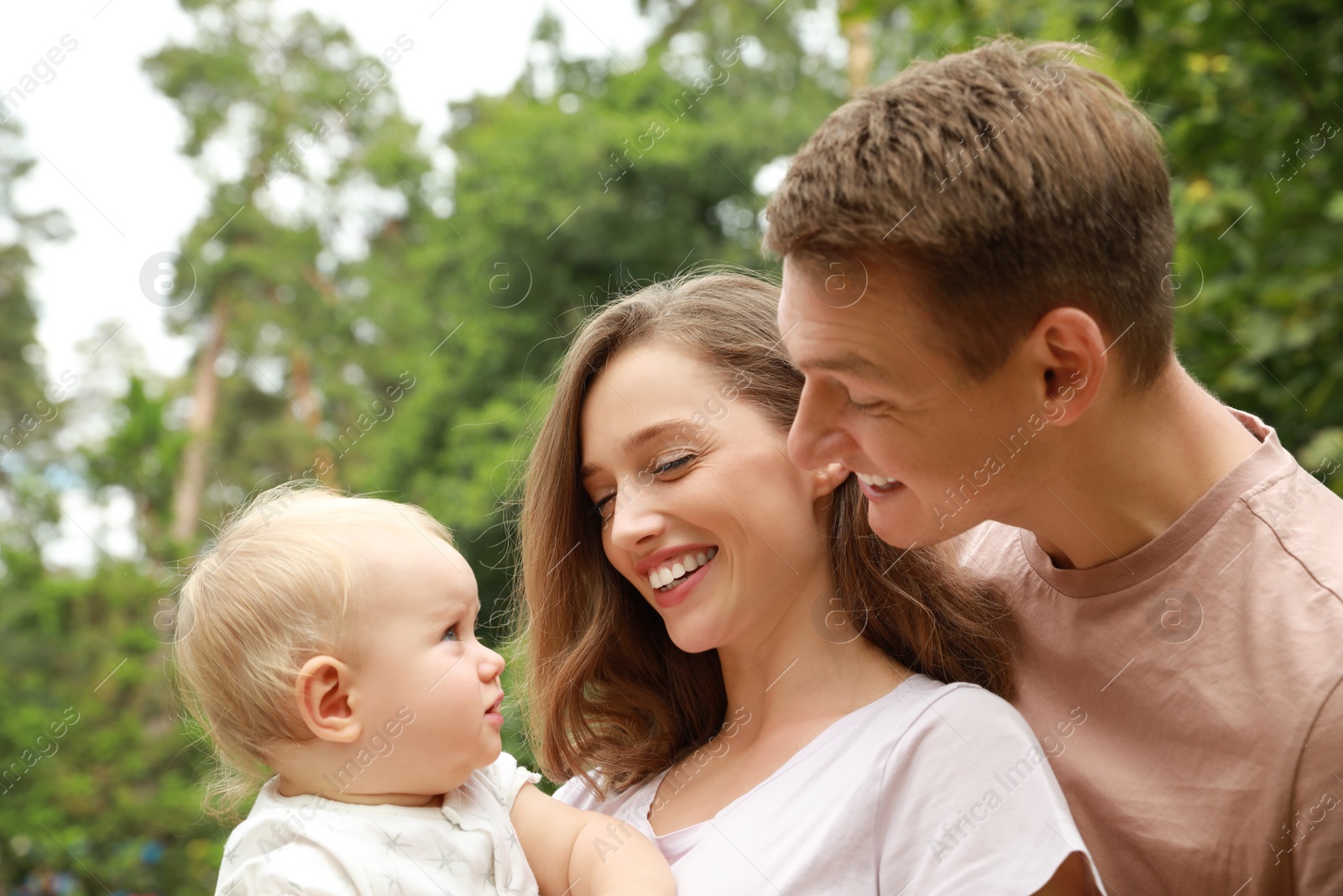 Photo of Parents with their cute baby spending time together outdoors. Happy family