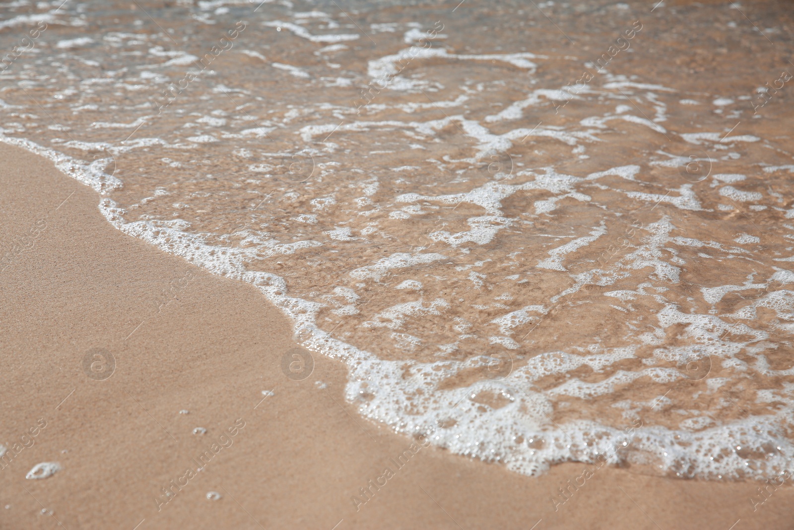 Photo of Beautiful sea waves on sandy beach, closeup