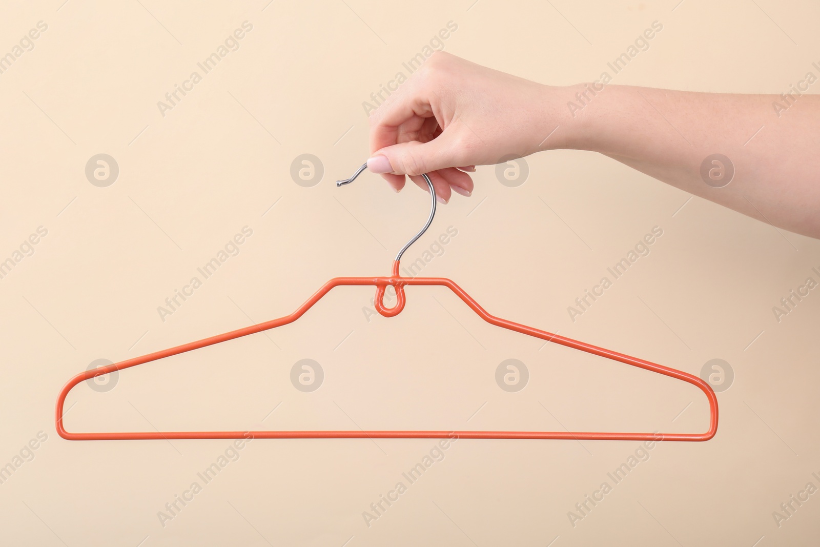Photo of Woman holding hanger on beige background, closeup