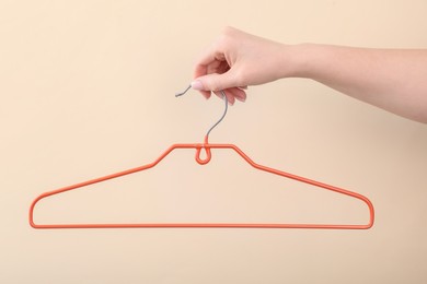 Photo of Woman holding hanger on beige background, closeup