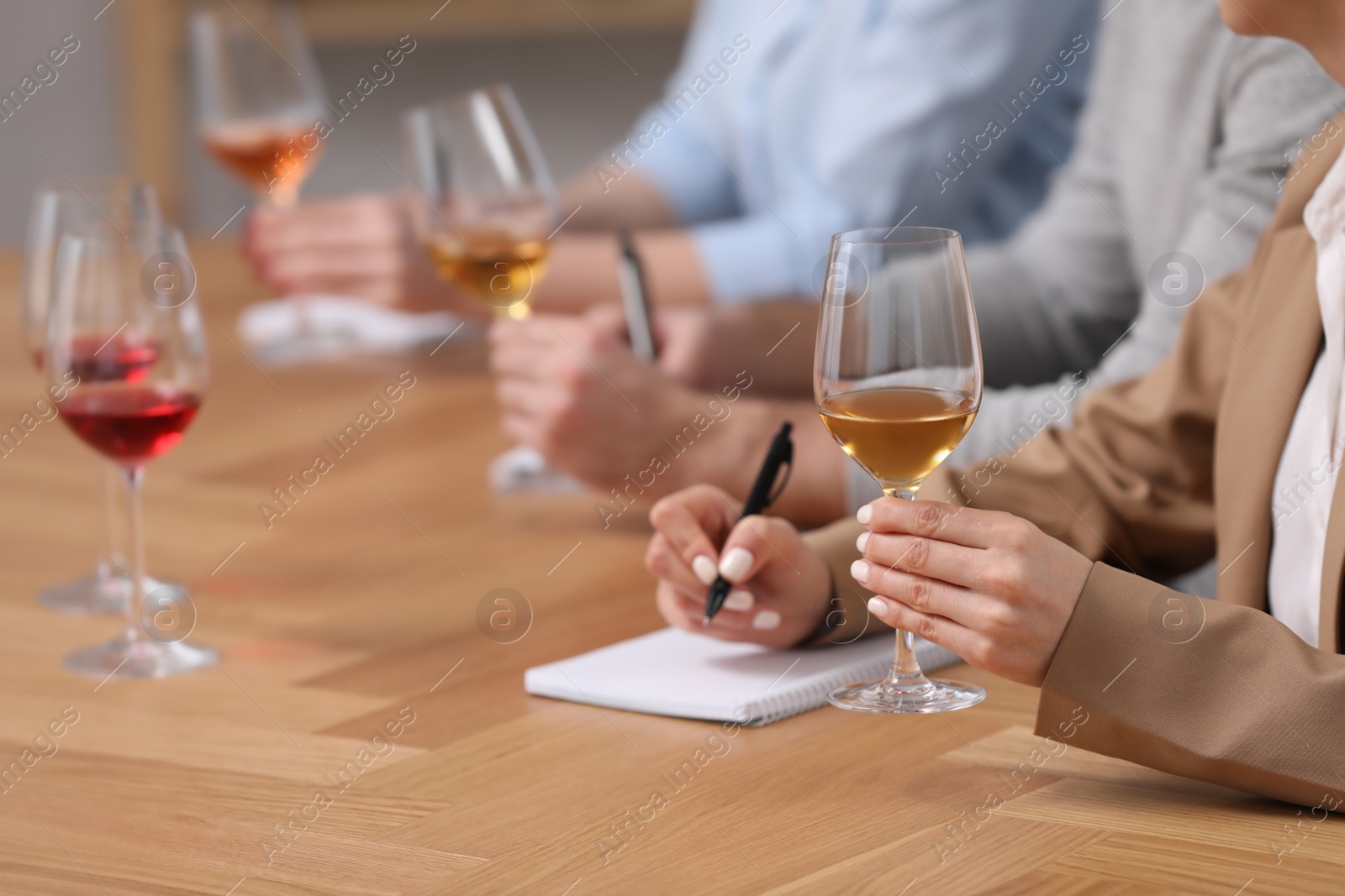 Photo of Sommeliers tasting different sorts of wine at table indoors, closeup