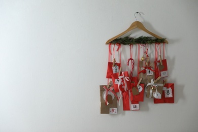 Photo of Handmade Advent calendar with gifts hanging on white wall, space for text. Christmas season