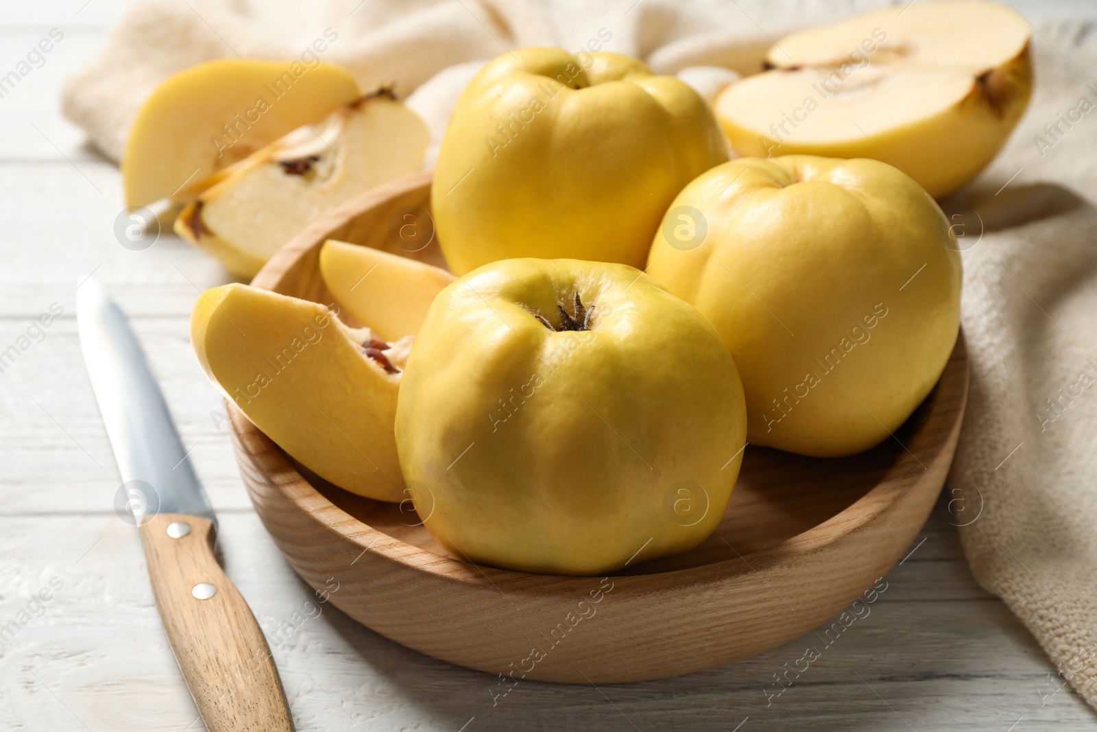 Photo of Fresh ripe organic quinces and knife on white wooden table