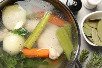 Pot with tasty bouillon on light grey table, flat lay